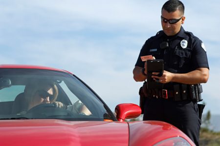 שוטר נותן דוח תנועה לאיש עם רכב אדום